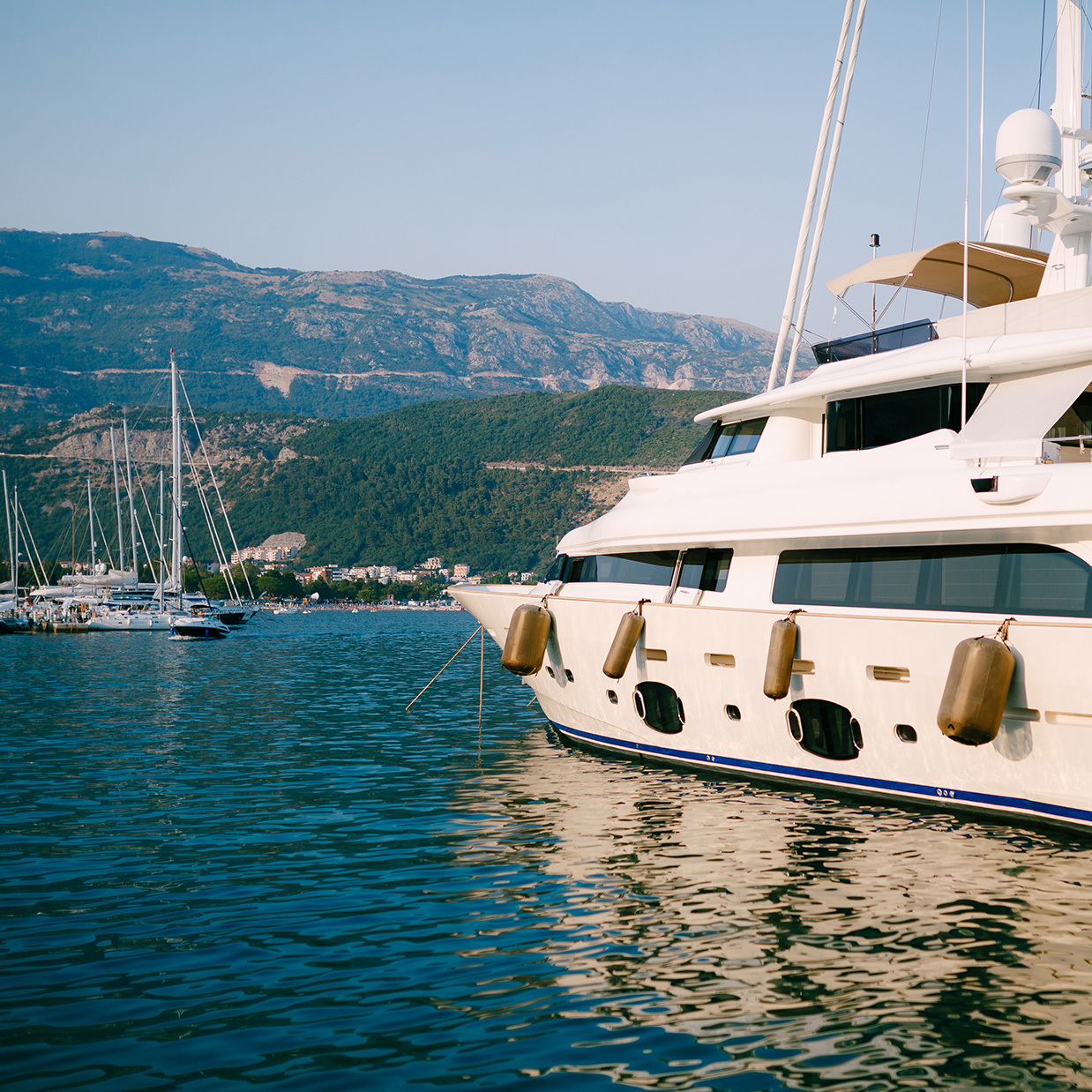 luxury-white-motor-yacht-sails-past-boat-dock-budva-montenegro